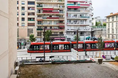 a red tram in a city with tall buildings at L39 Suite Promenade des Anglais, Vue Mer Terrasse&WIFI in Nice