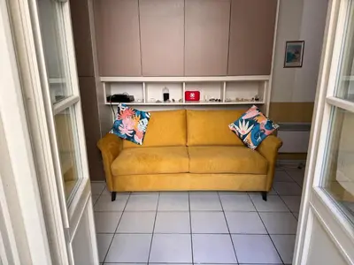 a yellow couch with two pillows in a living room at Grimaldi Central AC 2 terraces Wifi 5mins SEA in Nice