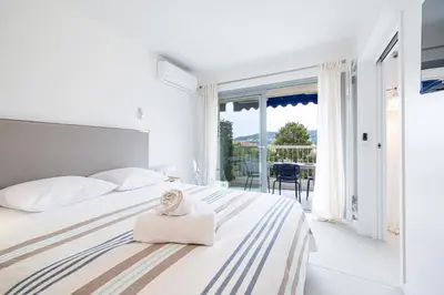 a white bedroom with a bed with a towel on it at FEEL HOME - GRASSEUIL in Saint-Jean-Cap-Ferrat
