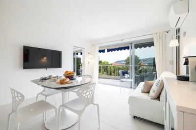 a white kitchen and living room with a table and chairs at FEEL HOME - GRASSEUIL in Saint-Jean-Cap-Ferrat