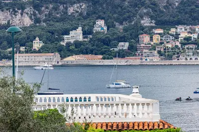 a white boat in the water near a city at FEEL HOME - GRASSEUIL in Saint-Jean-Cap-Ferrat