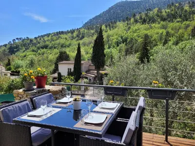 a table on a balcony with a view of a mountain at Chaleureuse bergerie rénovée. in Tourrette-Levens