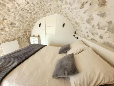 a bedroom with a bed with a stone wall at Chaleureuse bergerie rénovée. in Tourrette-Levens