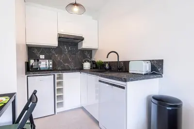 a kitchen with white cabinets and a sink at Pretty Studio Swimming pool and Sea in Cagnes-sur-Mer