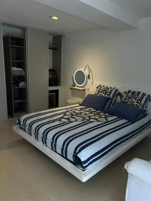 a bedroom with a large bed with blue pillows and a mirror at COTTAGE MARIN avec VUE MER in Nice