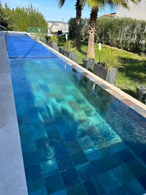 a blue swimming pool with a blue tiled floor at COTTAGE MARIN avec VUE MER in Nice