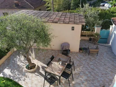 a patio with a wooden table and chairs and a tree at Villa Soleil Levant in Nice